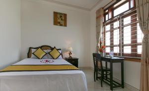 1 dormitorio con cama, escritorio y ventana en Snow Pearl Homestay Hoi An, en Hoi An