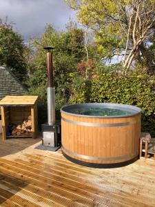a hot tub on a wooden deck with a stove at Rosebank Cottage - Hot Tub & Log Stove in Alexandria