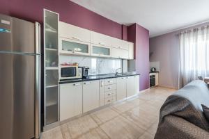 a kitchen with white cabinets and a purple wall at Main square apartment in Durrës