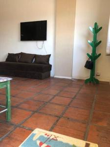 a living room with a couch and a tv on the wall at Lindo apartamento na lagoa de Iguaba in Iguaba Grande