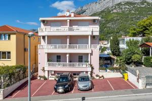 two cars parked in a parking lot in front of a building at Apartmani Podest in Baška Voda