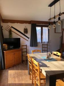 a dining room with a table and chairs and a television at chalet mitoyen en duplex in La Joue du Loup +29 photos