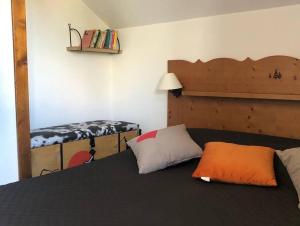 a bedroom with a bed with an orange pillow on it at chalet mitoyen en duplex in La Joue du Loup