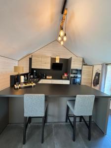 a kitchen with a large black counter and two chairs at Ambiance boisée Moustier in Stoumont
