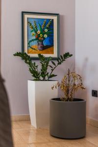 two potted plants sitting on the floor in front of a painting at Main square apartment in Durrës +20 photos