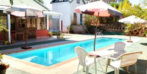 a pool with a table and two chairs and an umbrella at Ecole Lodge Antananarivo in Mahitsy