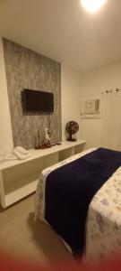 ein Schlafzimmer mit einem Bett und einem Flachbildfernseher in der Unterkunft Apartamento na Praia da Enseada, 100 mt praia in São Francisco do Sul