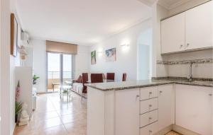 a kitchen with white cabinets and a living room at Lovely Apartment In Torrevieja in Torrevieja
