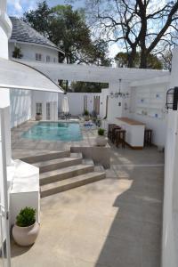 Un patio trasero con piscina y una casa. en 7 Woodmead Suites, en Johannesburgo