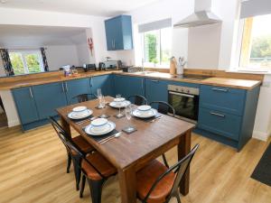 a kitchen with a wooden table and blue cabinets at Lobster Cottage in Saundersfoot