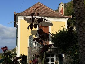 a yellow building with a balcony and an umbrella at Quinta das Hortênsias in Arco de São Jorge