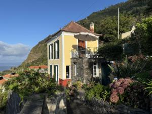 a yellow house with an umbrella on a hill at Quinta das Hortênsias in Arco de São Jorge +13 photos