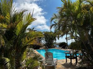 ティハラフェにあるVilla Feliz casa Los Geranios 2のヤシの木が植わるプール(椅子2脚、テーブル付)