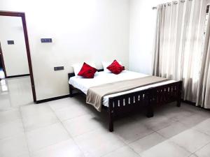 ein Schlafzimmer mit einem Bett mit roten Kissen darauf in der Unterkunft Krishnasila Homestay in Varkala