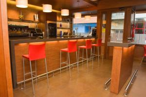 a bar with red bar stools in a kitchen at Hotel Marcial in Narón