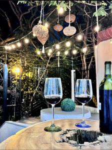 two wine glasses on a table with a bottle of wine at DG Divine Garden Tabasco in Villahermosa