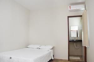 ein weißes Zimmer mit einem Bett und einem Spiegel in der Unterkunft Casa Da Onda in Tamandaré