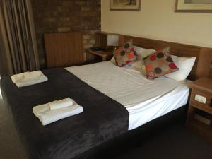 a bed in a hotel room with towels on it at Coomera Motor Inn in Gold Coast