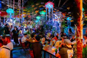a group of people sitting at tables in a restaurant at SECRET GARDEN Hostel - WANDERNEST Cat Ba in Cat Ba +42 photos