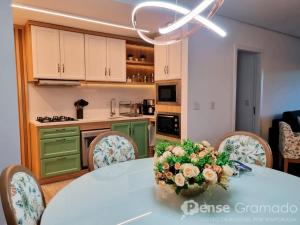 a kitchen with a table with a vase of flowers on it at Belluno Boulevard Canela in Canela
