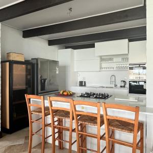 a kitchen with white cabinets and a island with bar stools at LaShack in Langebaan +32 photos