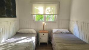 zwei Einzelbetten in einem Zimmer mit Fenster in der Unterkunft Los Alamos in San Carlos de Bariloche