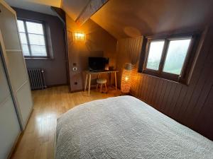 a bedroom with a bed and a desk and two windows at Gîte marguerite in Sainte-Marie-aux-Mines