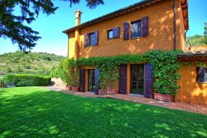 a house with a green yard in front of it at Casale Argentario by PosarelliVillas in Porto Santo Stefano