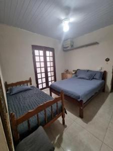 a bedroom with two beds and a window at Casa com piscina em Bertioga 700m da praia in Bertioga