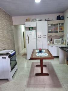 a kitchen with white cabinets and a table in it at Casa com piscina em Bertioga 700m da praia in Bertioga