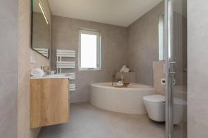 a bathroom with a tub and a sink and a toilet at Hello Zeeland - Appartement Kusthuys 2 - 2025 in Zoutelande