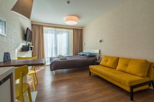 New Gudauri Studio near main Gondola lifts في غودواري: غرفة معيشة بسرير واريكة صفراء