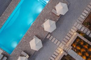 an overhead view of tables and umbrellas next to a pool at Archon Seaside Retreat in Plaka