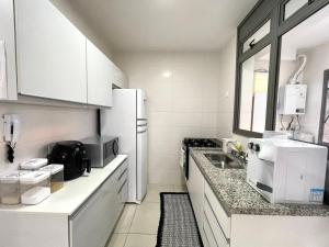 a kitchen with a white refrigerator and a sink at TULUM Bertioga - belo apartamento com vista para o mar in Bertioga +31 photos