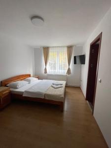 a bedroom with a large bed and a window at Pensiunea Vătafu in Gura Râului