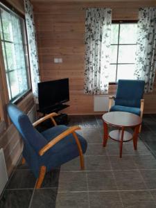 a living room with two chairs and a table and a tv at Katajaranta in Karvonen