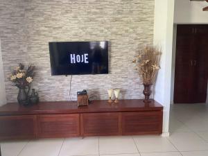 einen TV an einer Backsteinwand mit einer Holzkommode in der Unterkunft Casa pé na areia na praia de Antunes em Maragogi in Maragogi