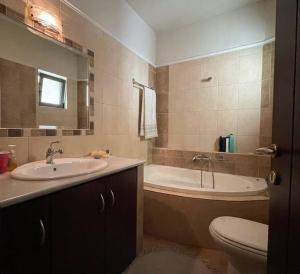 a bathroom with a sink and a tub and a toilet at Full House Trikala Escape in Tríkala