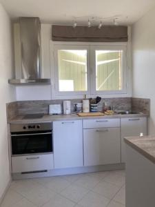 een keuken met witte kasten, een fornuis en een raam bij La rouvraie in Flayosc +3 foto's