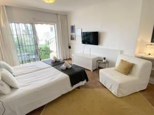 ein weißes Schlafzimmer mit einem Bett und einem Stuhl in der Unterkunft N02 Los Rosales - Studio in Sitio de Calahonda