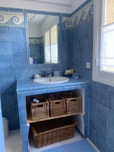 een blauwe badkamer met een wastafel en een spiegel bij La rouvraie in Flayosc