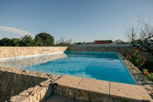 a swimming pool with a stone retaining wall and anergynergynergynergyploadpload at Tree House - Casa Laranjeira in Quinta do Conde