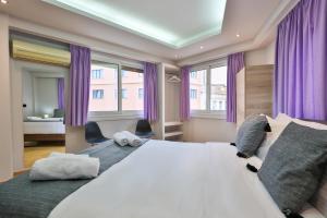 Un dormitorio con una cama grande y cortinas moradas. en 1 BD Athens Nikiou Cosy Apartment by Live&Travel, en Atenas