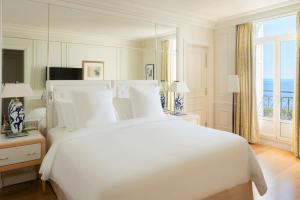 a bedroom with a large white bed and a large mirror at Grand-Hôtel du Cap-Ferrat, A Four Seasons Hotel in Saint-Jean-Cap-Ferrat