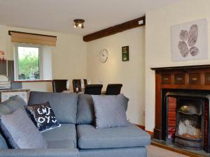 a living room with a blue couch and a fireplace at Brackendale Cottage - Uk1335 in Threlkeld