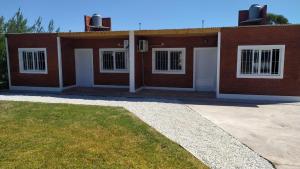 a red brick house with white doors and a yard at duplex playa marisol in Balneario Oriente