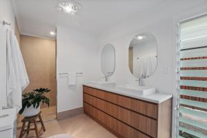 ein Badezimmer mit zwei Waschbecken und einem Spiegel in der Unterkunft Seaspray - 93 Tramican Street in Point Lookout + 11 Fotos