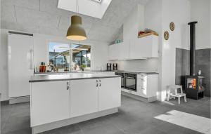 a kitchen with white cabinets and a fireplace at Nice Home In Bogense With Wifi in Bogense