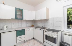 a kitchen with white cabinets and a sink and a window at 2 Bedroom Gorgeous Apartment In Pobri in Volosko