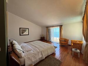 a bedroom with a bed and a chair and a window at Suite Bela Vigia 2 in Jardim do Mar
